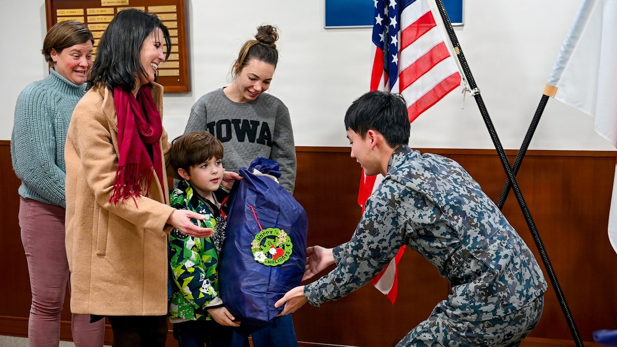 A Japan Air Self-Defense Force (JASDF) Airman assigned to the 3rd Air Wing hands a gift bag to a Misawa Cookie Caper volunteer at Misawa Air Base, Japan, Dec. 15, 2025. JASDF Airmen returned the gesture with gift bags after receiving cookies from volunteers the week prior, underscoring the community connections that contribute to unity across Misawa. (U.S. Air Force photo by Airman 1st Class Hannah Bench)