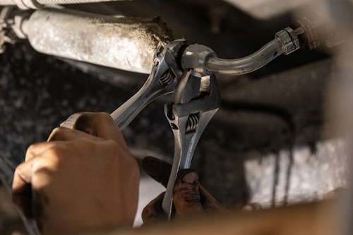 Two hands grasping two crescent wrenches securing a new piece of equipment.