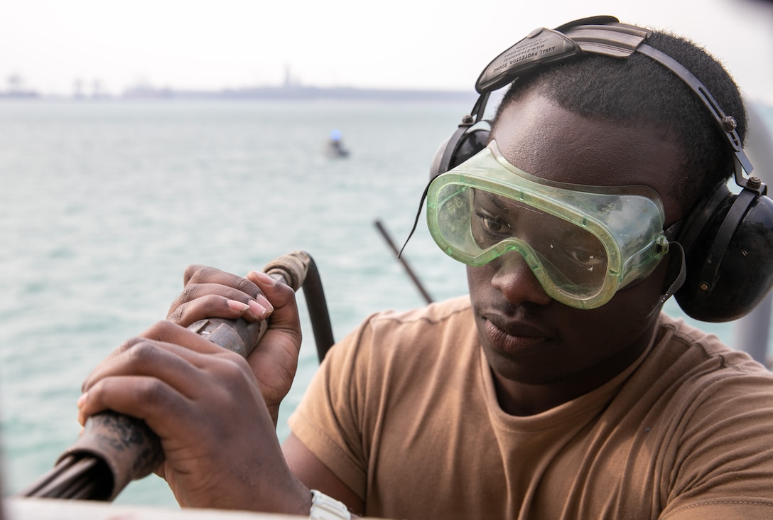 U.S. Navy Cryptologic Technician (Collection) Seaman Chaplain Adusei uses a needle gun for deck preservation on the foc’sle of the Arleigh Burke-class guided-missile destroyer USS Mitscher (DDG 57), Jan. 5, 2025. Mitscher is deployed to the U.S. 5th Fleet area of operations to support maritime security and stability in the U.S. Central Command area of responsibility.