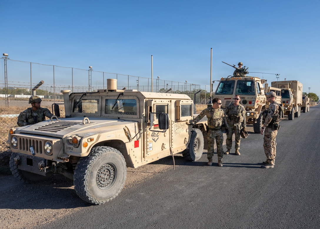 U.S. and German Soldiers coordinate and discuss movement plans prior to the convoy departure to Beneswala Range at Erbil Air Base on Oct. 31, 2025. Pre-mission communication enhanced cohesion and ensured safe, synchronized travel for the multinational formation. (U.S. Army photo by Spc. Doniel Kennedy.)