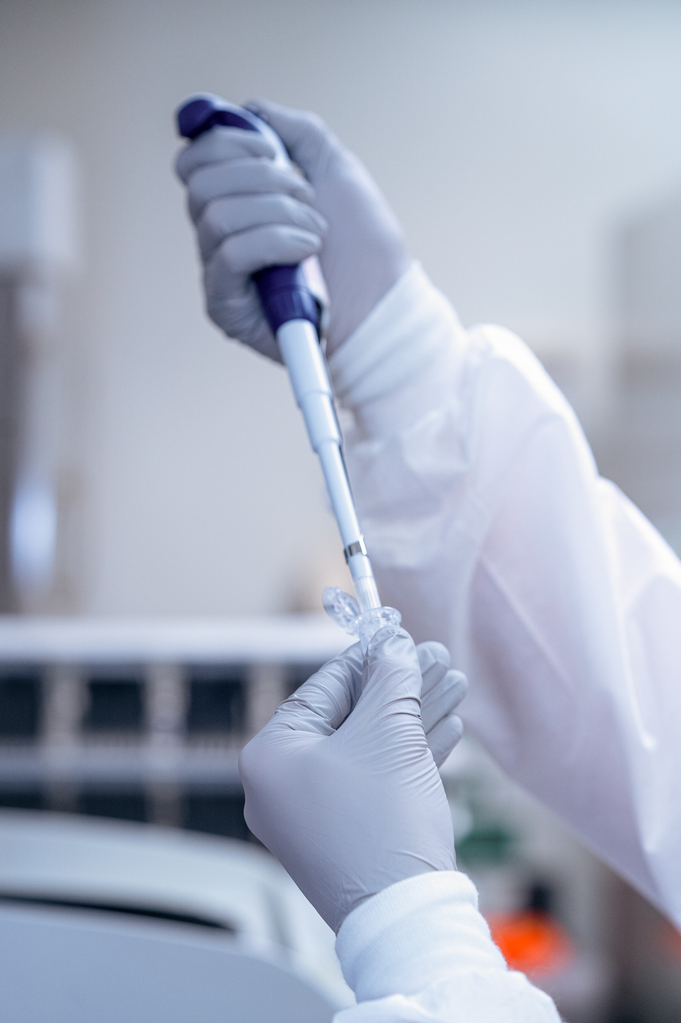 Two hands in blue latex gloves pipettes fluid.