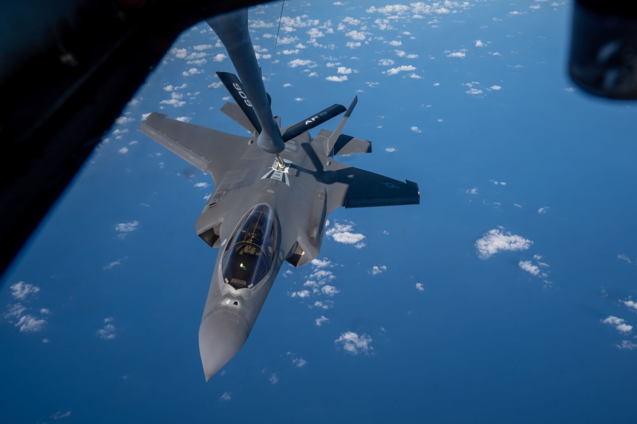 The boom from a military refueling aircraft connects to a military fighter jet during an aerial refueling mission.