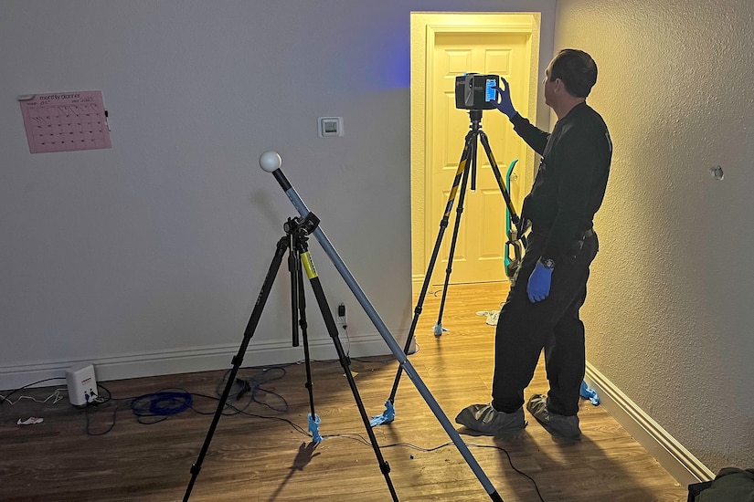 A man stands in a room while using imaging equipment.