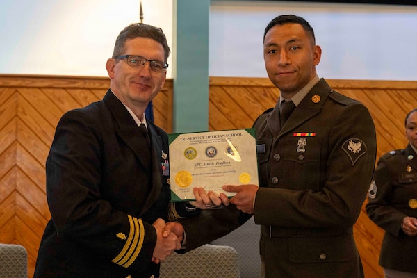 251216-N-JC800-1022 YORKTOWN, Virginia (Dec. 16, 2025) - Cmdr. Joshua Keil, Dean, Tri-Service Optician School, presents a certificate of completion to U.S. Army Spc. Ashish Pradhan during the graduation ceremony for the TOPS Class 25010, Dec. 16. (U.S. Navy photo by Mass Communication Specialist 1st Class Heath Zeigler/Released)