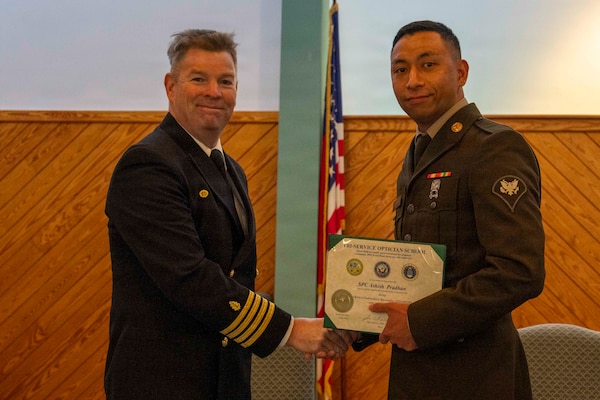 251216-N-JC800-1026 YORKTOWN, Virginia (Dec. 16, 2025) - Capt. James Corbett, commanding officer of Naval Medical Leader and Professional Development Command, presents a certificate of completion to U.S. Army Spc. Ashish Pradhan during the graduation ceremony for the Tri-Service Optician School Class 25010, Dec. 16. (U.S. Navy photo by Mass Communication Specialist 1st Class Heath Zeigler/Released)
