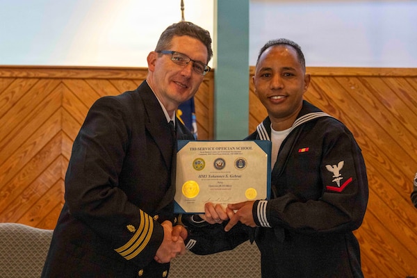 251216-N-JC800-1022 YORKTOWN, Virginia (Dec. 16, 2025) - Cmdr. Joshua Keil, Dean, Tri-Service Optician School, presents a certificate of completion to Hospital Corpsman 3rd Class Yohannes Gerbrai during the graduation ceremony for the TOPS Class 25010, Dec. 16. (U.S. Navy photo by Mass Communication Specialist 1st Class Heath Zeigler/Released)