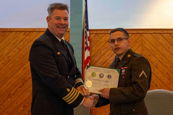 251216-N-JC800-1043 YORKTOWN, Virginia (Dec. 16, 2025) - Capt. James Corbett, commanding officer of Naval Medical Leader and Professional Development Command, presents a certificate of completion to U.S. Army Pvt. Gilbert San Miguel during the graduation ceremony for the Tri-Service Optician School Class 25010, Dec. 16. (U.S. Navy photo by Mass Communication Specialist 1st Class Heath Zeigler/Released)