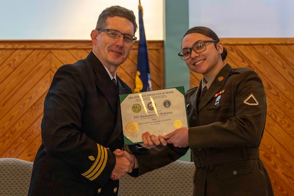 251216-N-JC800-1046 YORKTOWN, Virginia (Dec. 16, 2025) - Cmdr. Joshua Keil, Dean, Tri-Service Optician School, presents a certificate of completion to U.S. Army Pfc. Rayohnalee Rodriguez during the graduation ceremony for the TOPS Class 25010, Dec. 16. (U.S. Navy photo by Mass Communication Specialist 1st Class Heath Zeigler/Released)