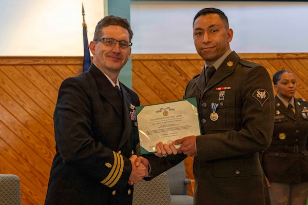 251216-N-JC800-1065 YORKTOWN, Virginia (Dec. 16, 2025) - Cmdr. Joshua Keil, Dean, Tri-Service Optician School, presents a U.S. Army Achievement Medal  to U.S. Army Spc. Ashish Pradhan during the graduation ceremony for the TOPS Class 25010, Dec. 16. (U.S. Navy photo by Mass Communication Specialist 1st Class Heath Zeigler/Released)