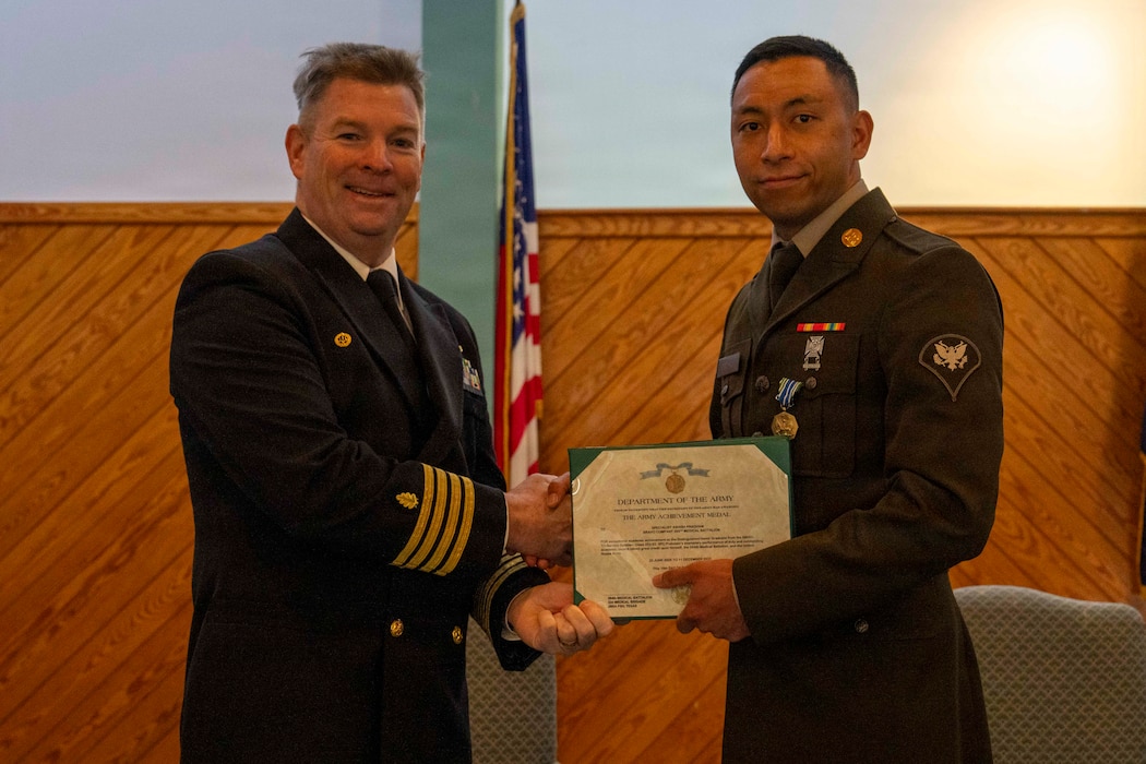 251216-N-JC800-1022 YORKTOWN, Virginia (Dec. 16, 2025) - Capt. James Corbett, commanding officer of Naval Medical Leader and Professional Development Command, presents a U.S. Army Achievement Medal to U.S. Army Pfc. Ashish Pradham during the graduation ceremony for the Tri-Service Optician School Class 25010, Dec. 16. (U.S. Navy photo by Mass Communication Specialist 1st Class Heath Zeigler/Released)