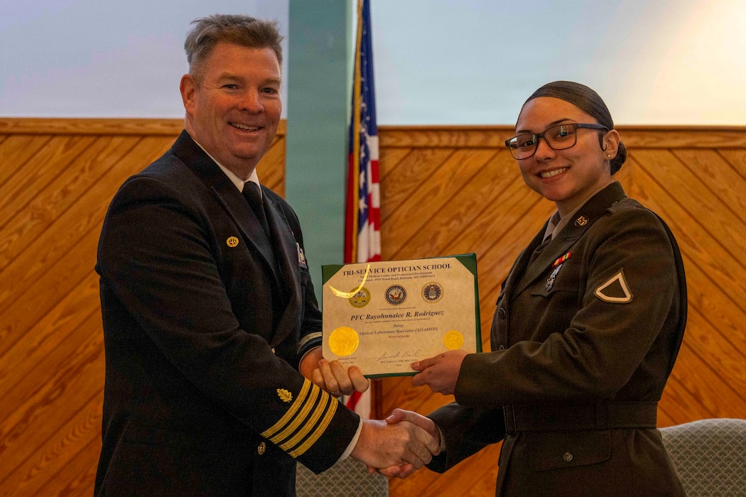 251216-N-JC800-1049 YORKTOWN, Virginia (Dec. 16, 2025) - Capt. James Corbett, commanding officer of Naval Medical Leader and Professional Development Command, presents a certificate of completion to U.S. Army Pfc. Rayohnalee Rodriguez during the graduation ceremony for the Tri-Service Optician School Class 25010, Dec. 16. (U.S. Navy photo by Mass Communication Specialist 1st Class Heath Zeigler/Released)