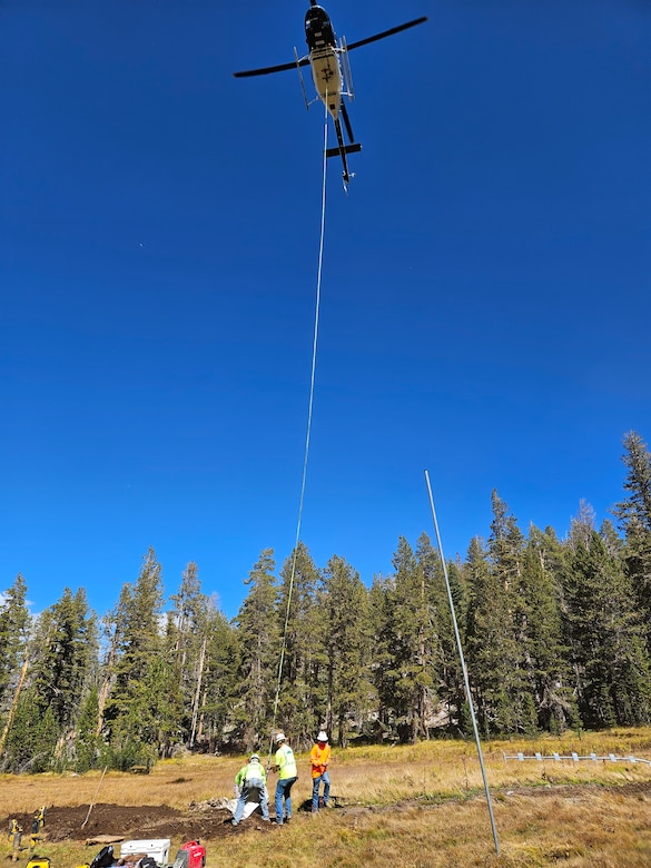 Helicopter with long rope hanging down to pick up rocks.