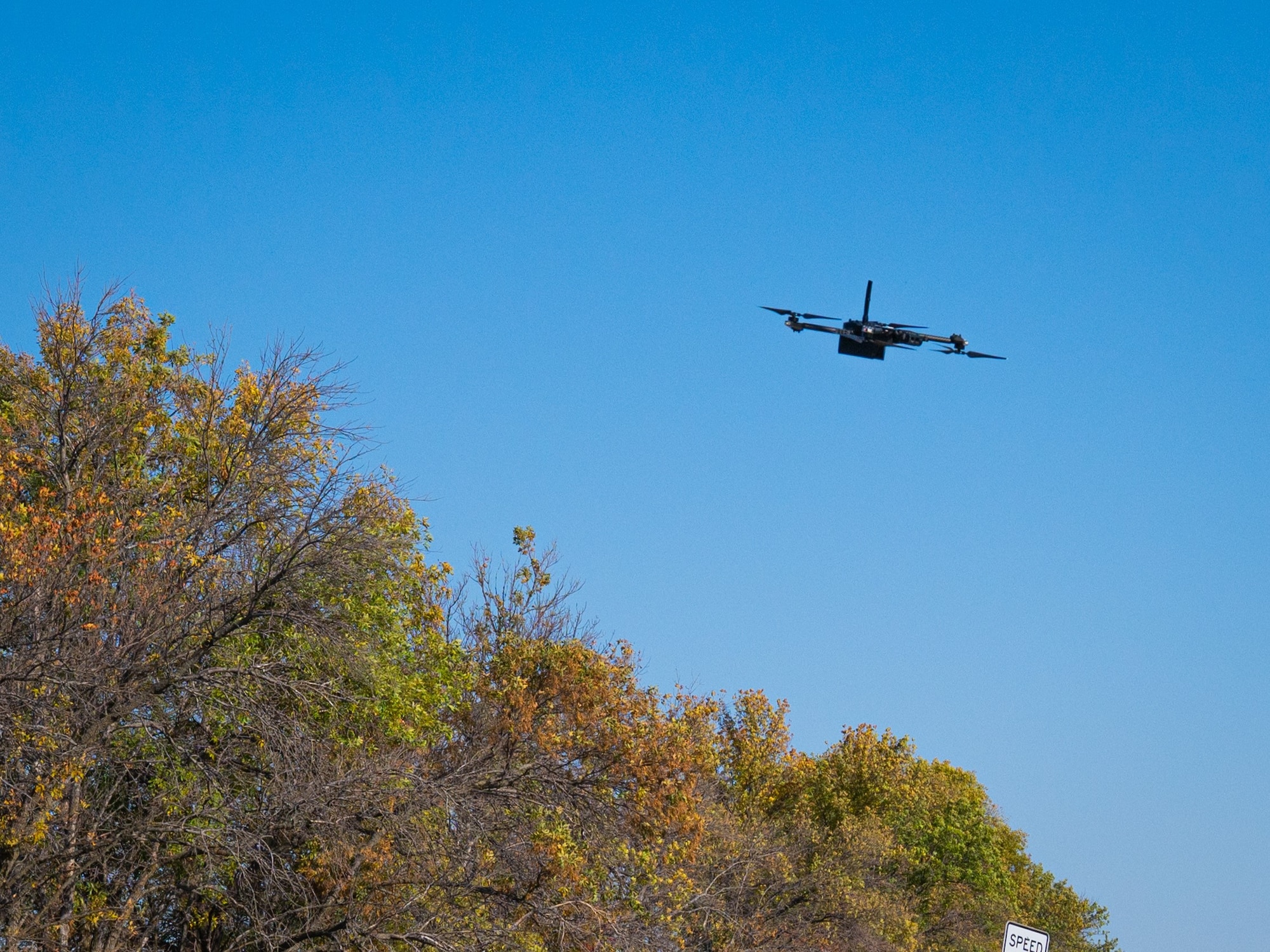 A small UAS flies in front of a blue sky.