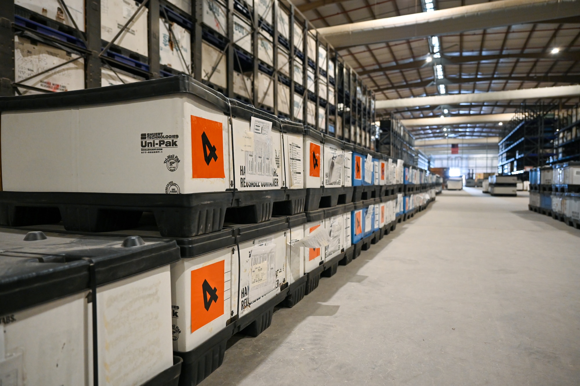 Bins line the floor and wall to the left in a warehouse