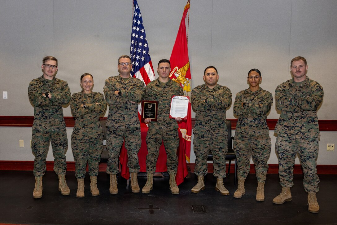 U.S. Marines with Distribution Management Instruction Company, Ground Supply School, pose for a group photo after awarding Staff Sgt. Cesar Espinoza-Alvarez, an instructor with Distribution Management Instruction Company, GSS, and a native of New Mexico, the National Defense Transportation Association Logistics Transportation Instructor of the Year award on Camp Gilbert H. Johnson, North Carolina.