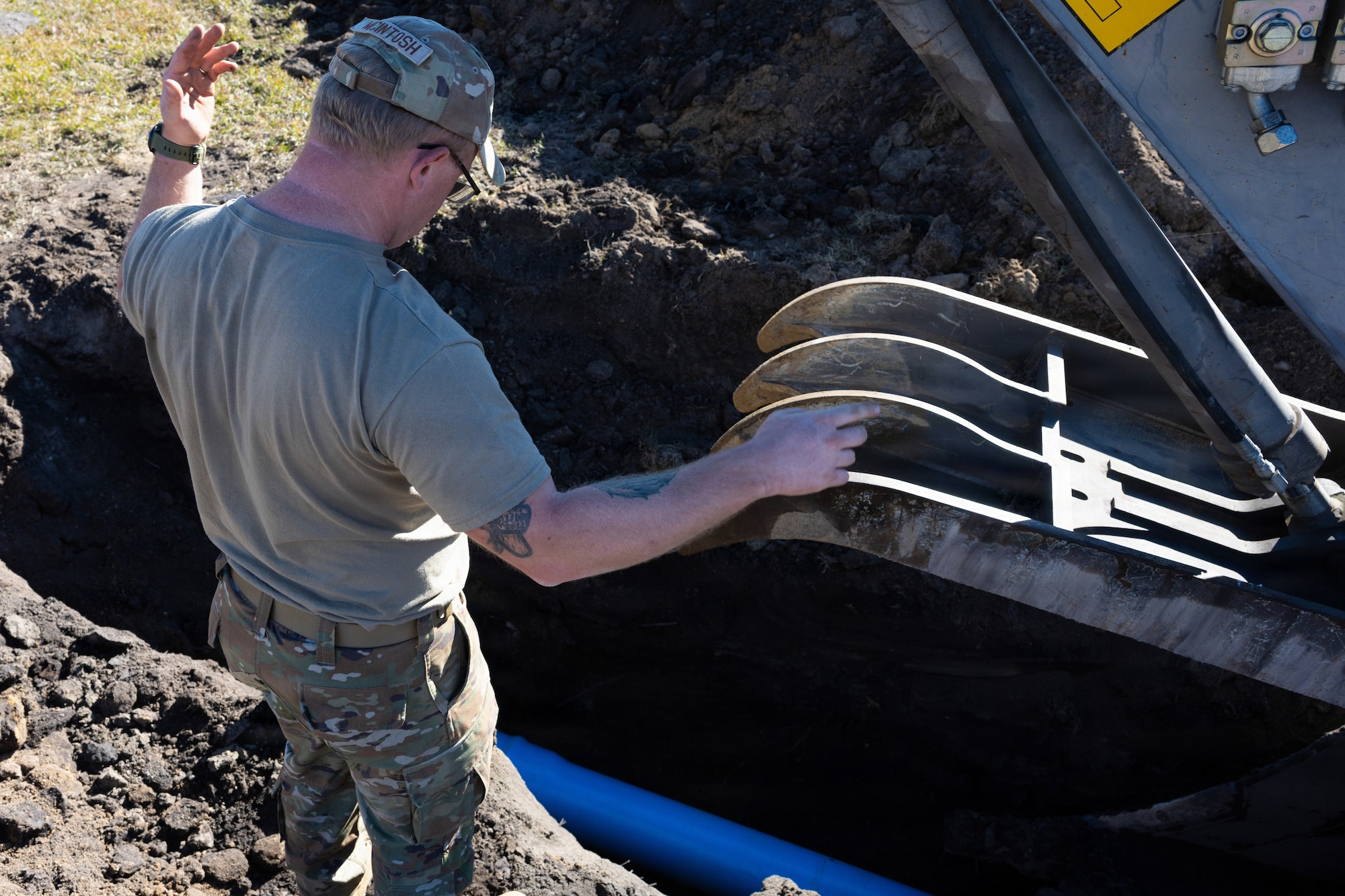 U.S. Air Force Tech. Sgt. Robert Mcintosh, 4th Civil Engineer Squadron pavement and equipment craftsman, signals to a heavy equipment operator while replacing a water line at Seymour Johnson Air Force Base, North Carolina, Nov. 17, 2025. The outdated pipes were replaced with new, stronger materials to increase longevity and effectiveness throughout the base. (U.S. Air Force photo by Airman Daryl Briscoe)