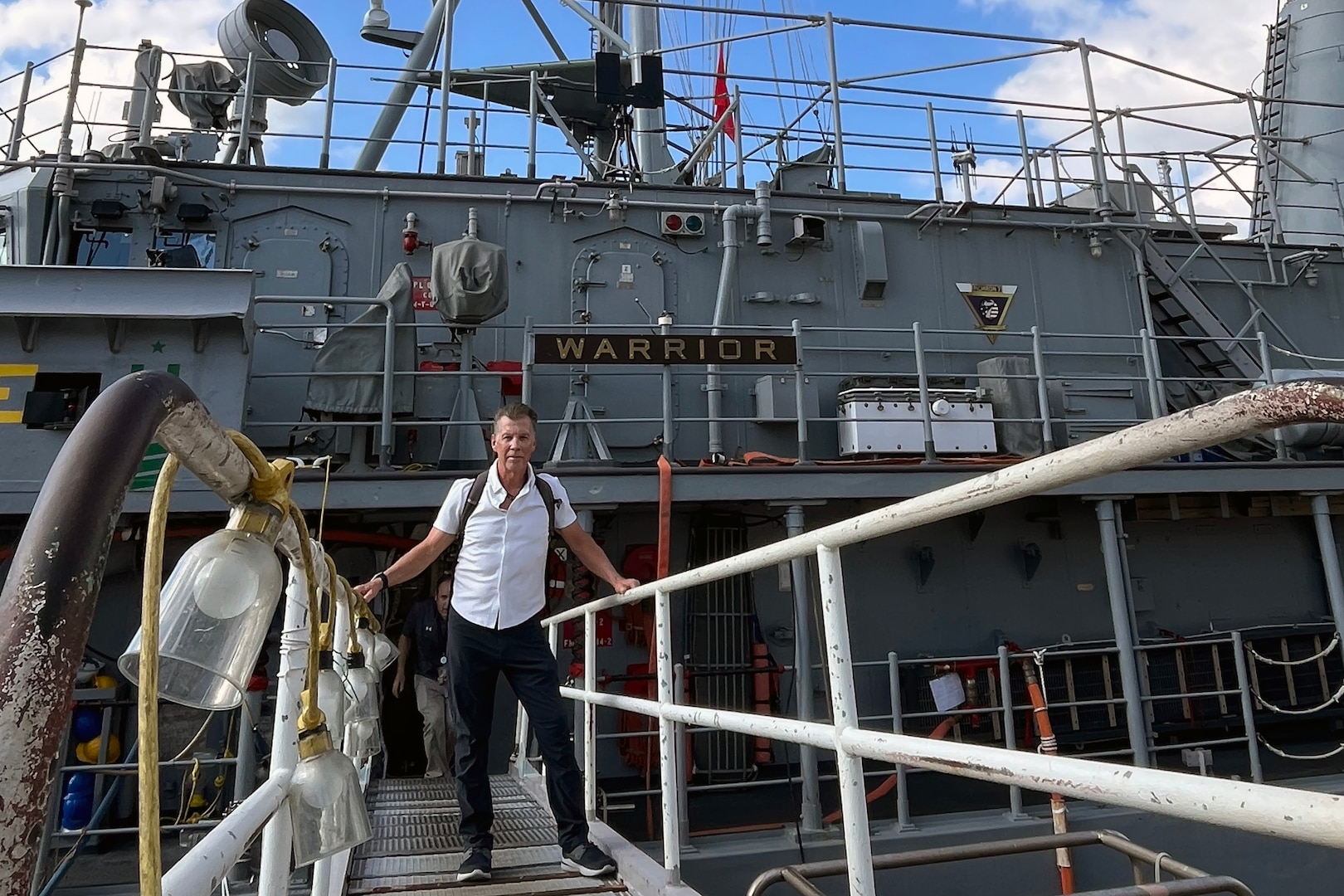 A man stands on the gangway leading up to a ship. He is in civilian cloths.