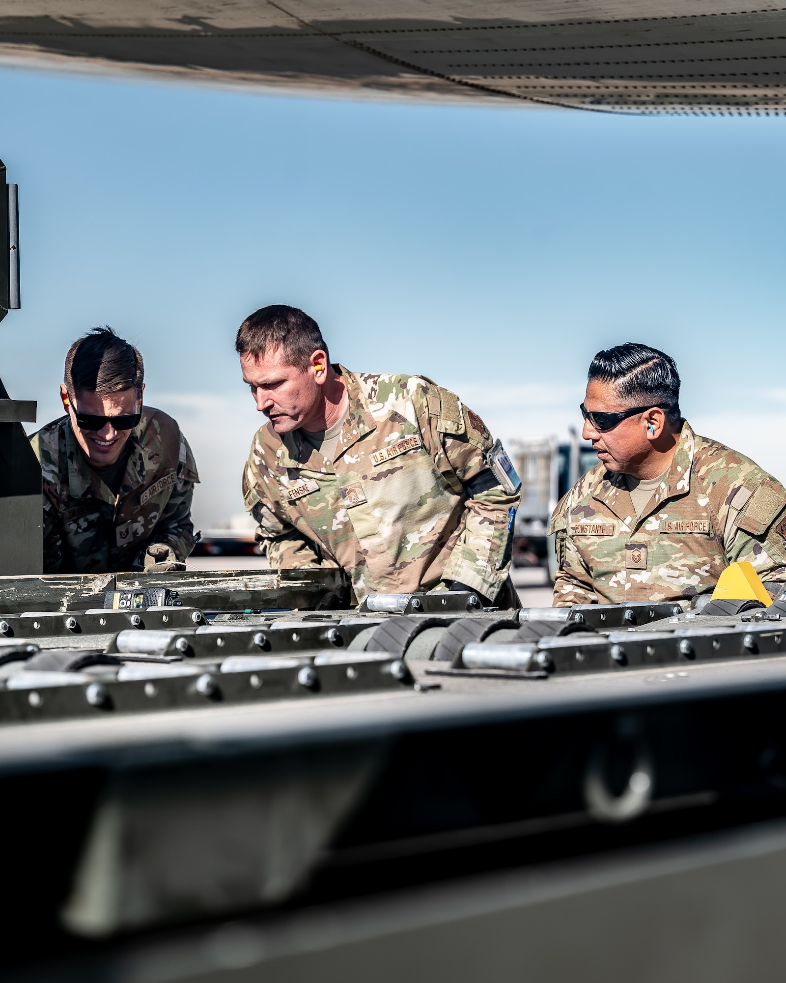 U.S. Air Force Tech. Sgt. Erik Swanberg (left), 161st Logistics Readiness Squadron air transportation operations center section supervisor, Chief Master Sgt. Chad Fenske (middle), 56th LRS senior enlisted leader, and Master Sgt. Rene Constante (right), 161st LRS air terminal function section chief, prepare a K-Loader for cargo pallets