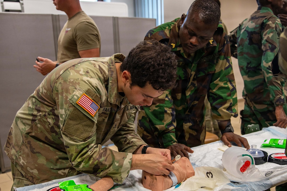 A U.S. soldier and partners work on a small, makeshift simulated casualty on a table.