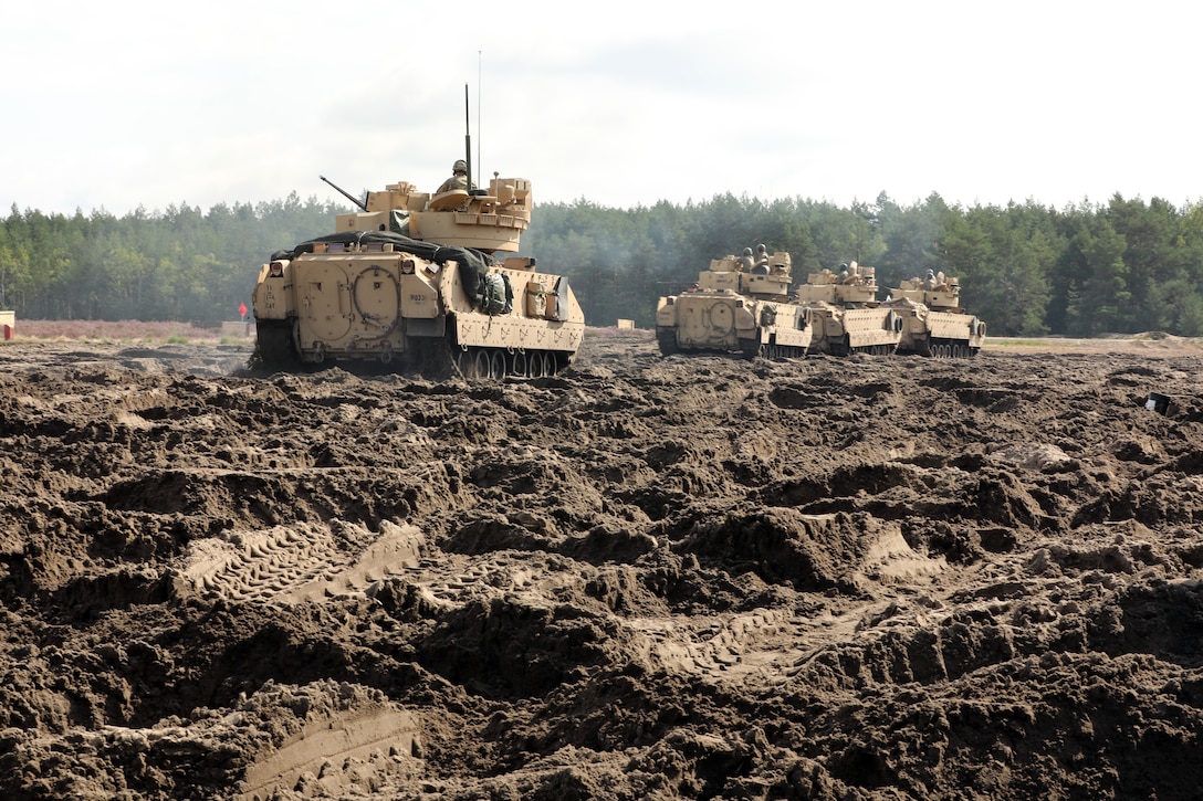 Bradley Fighting Vehicle crew members of 1st Squadron, 4th Cavalry Regiment (1-4), 1st Armored Brigade Combat Team, 1st Infantry Division align their tanks in mud as part of gunnery table VI qualifications to maintain readiness in Świętoszówka, Poland, Sept. 1, 2021. A rotational forward presence throughout Europe enables deterrence and defense against threats from any direction at any time. (U.S. Army photo by Sgt. 1st Class Chad Menegay/RELEASED)