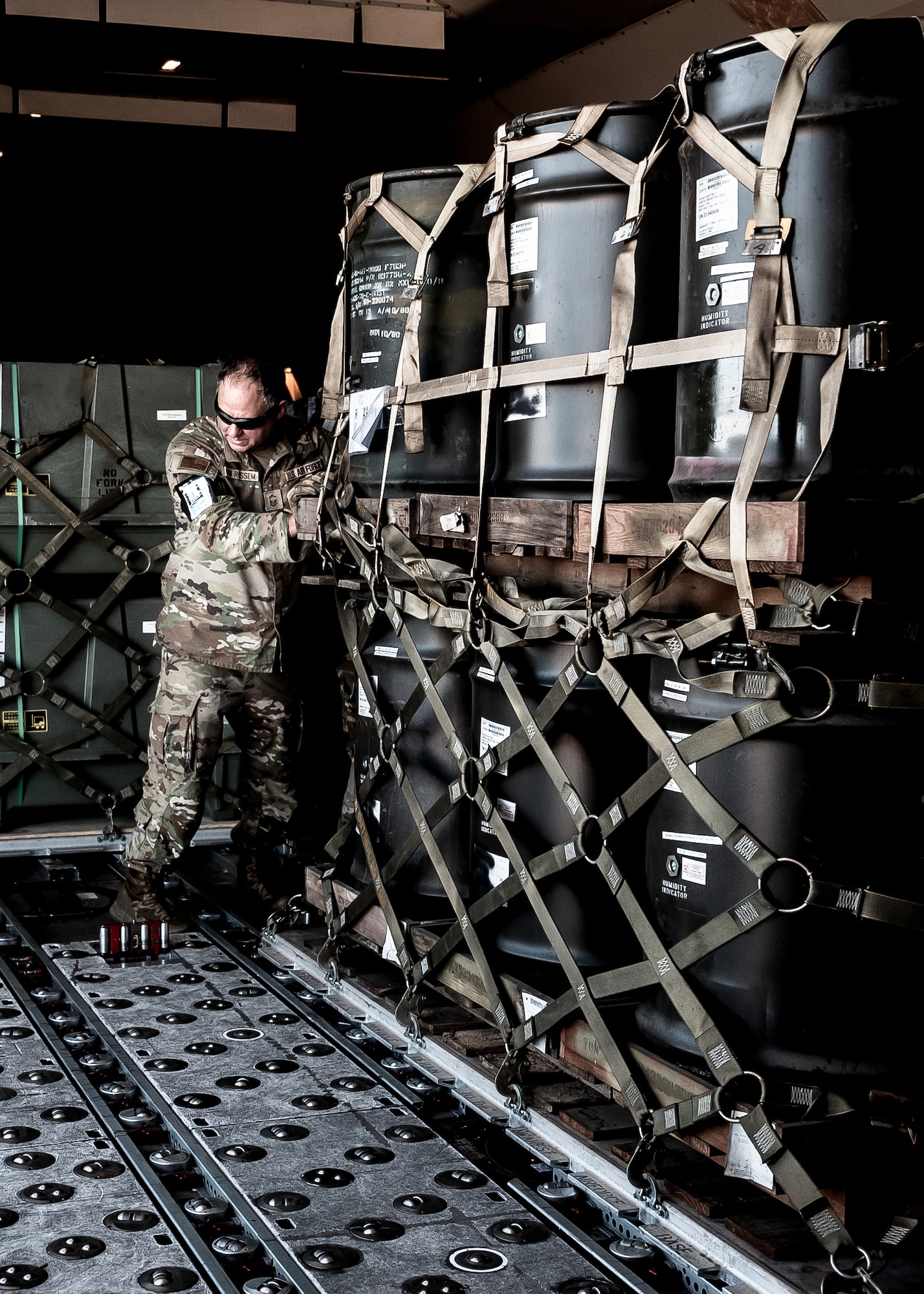 U.S. Air Force Senior Master Sgt. Matthew Van Rossem, 161st Logistics Readiness Squadron traffic management office superintendent, pushes a cargo pallet of munitions tail kits during Special Assignment Airlift Mission