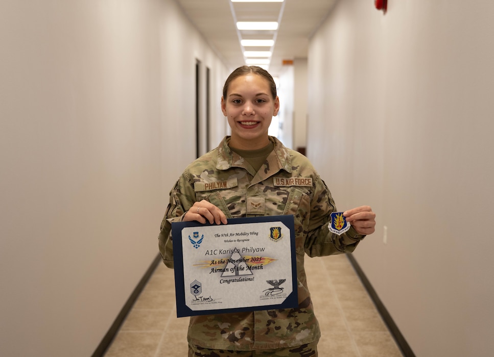 U.S. Air Force Airman 1st Class Karissa Philyaw, 97th Operations Support Squadron airfield management operations coordinator, displays her coin and November Airman of the Month Award at Altus Air Force Base, Oklahoma, Dec. 17, 2025. Within her involvement in the 97th Operations Support Squadron Moral Committee, she raised over $2,000 over the last three months. (U.S. Air Force photo by Airman 1st Class Emma Wright)