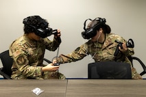 U.S. Air Force Airman Bianca Rondero, 48th Intelligence Support Squadron cyber systems operator, assists Airman Valerie Escotto-Rivera, 13th Intelligence Squadron signal intelligence analyst, as they use virtual reality (VR) headgear installed with Moth+Flame programming while a professional development course at Recce U, December 12, 2025, at Beale Air Force Base, California.