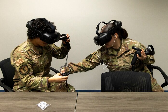 U.S. Air Force Airman Bianca Rondero, 48th Intelligence Support Squadron cyber systems operator, assists Airman Valerie Escotto-Rivera, 13th Intelligence Squadron signal intelligence analyst, as they use virtual reality (VR) headgear installed with Moth+Flame programming while a professional development course at Recce U, December 12, 2025, at Beale Air Force Base, California.