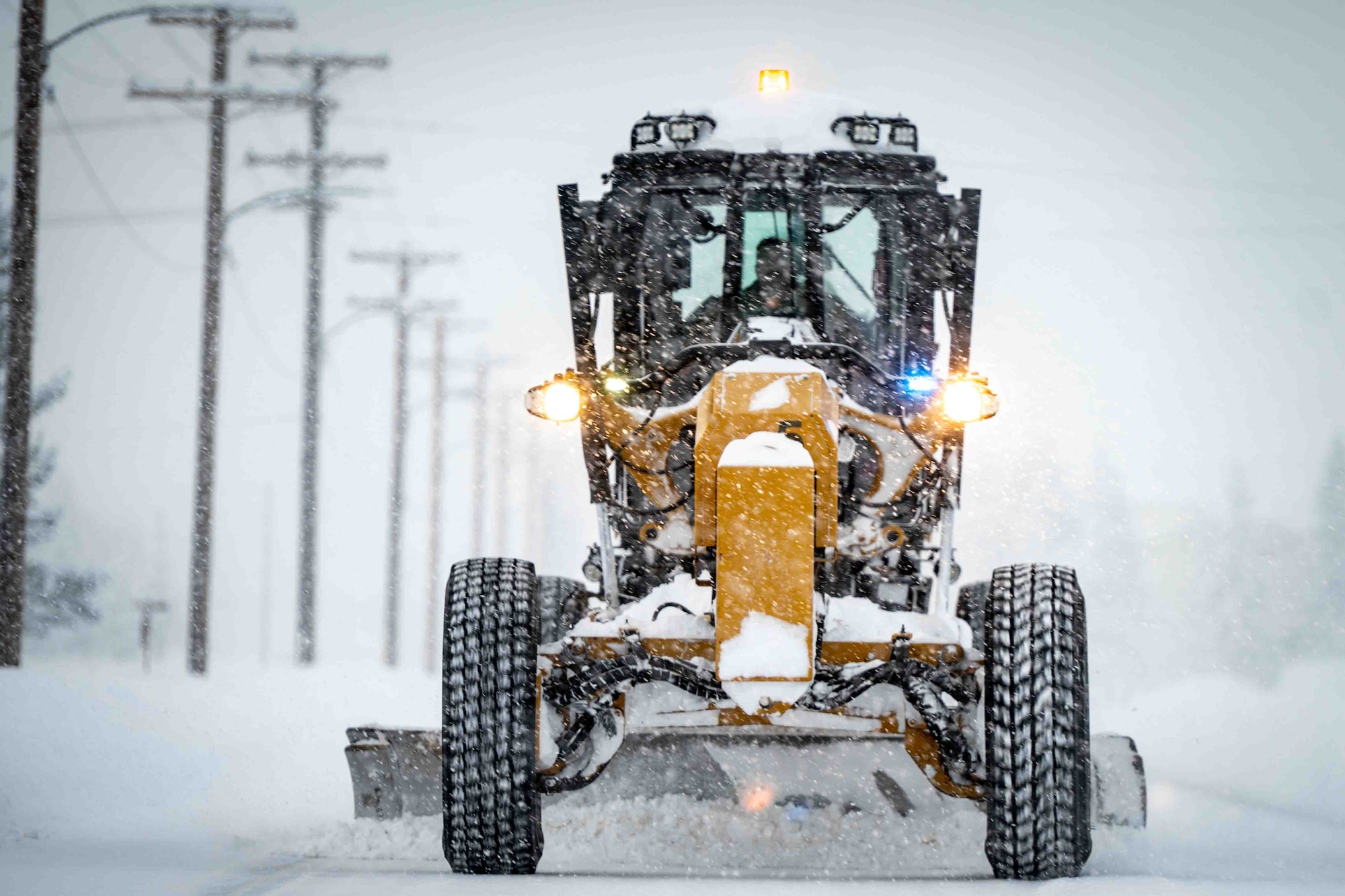 A member of the U.S. Air Force’s 773d Logistics Readiness Squadron operates a road grader to level roads after heavy snowfall at Joint Base Elmendorf-Richardson, Alaska, Jan. 6, 2026. Maintaining clear roadways during snowfall ensures the base remains fully operational, reinforcing ready Airmen, ready base, and ready community objectives. (U.S. Air Force photo by Senior Airman Hunter Hites)