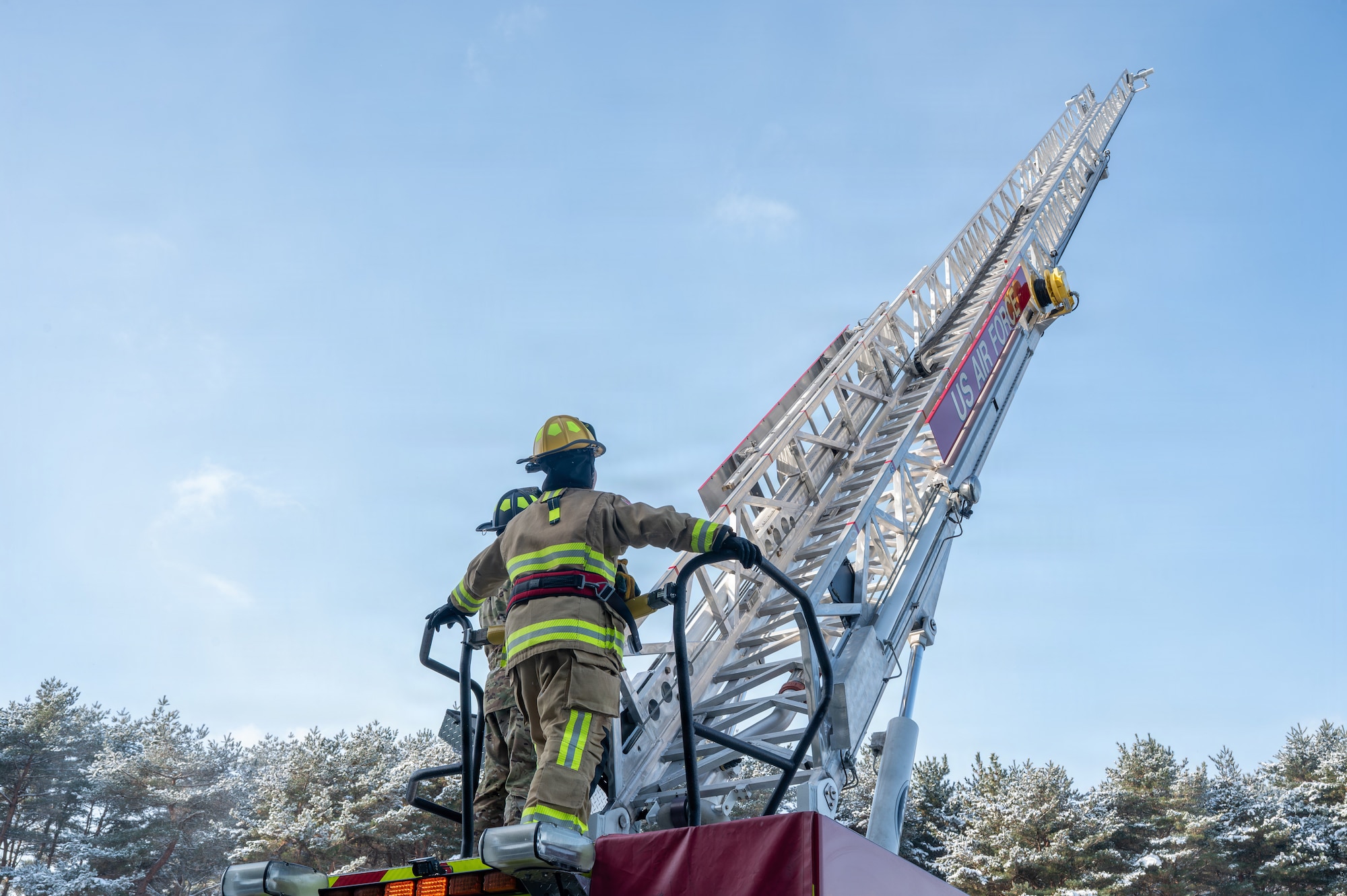 U.S. Air Force Airman 1st Class Jasmin Gonzalez, left, 35th Civil Engineer Squadron fire protection specialist, prepares to climb an aerial ladder with guidance from SrA Bode Hartwig, 35th Civil Engineer Squadron fire protection specialist, at Misawa Air Base, Japan, Jan. 6, 2026. Firefighters serve as a key force protection element, delivering emergency response to safeguard people, aircraft, and mission-critical facilities at Misawa Air Base. (U.S. Air Force photo by Airman 1st Class Adryan Young)