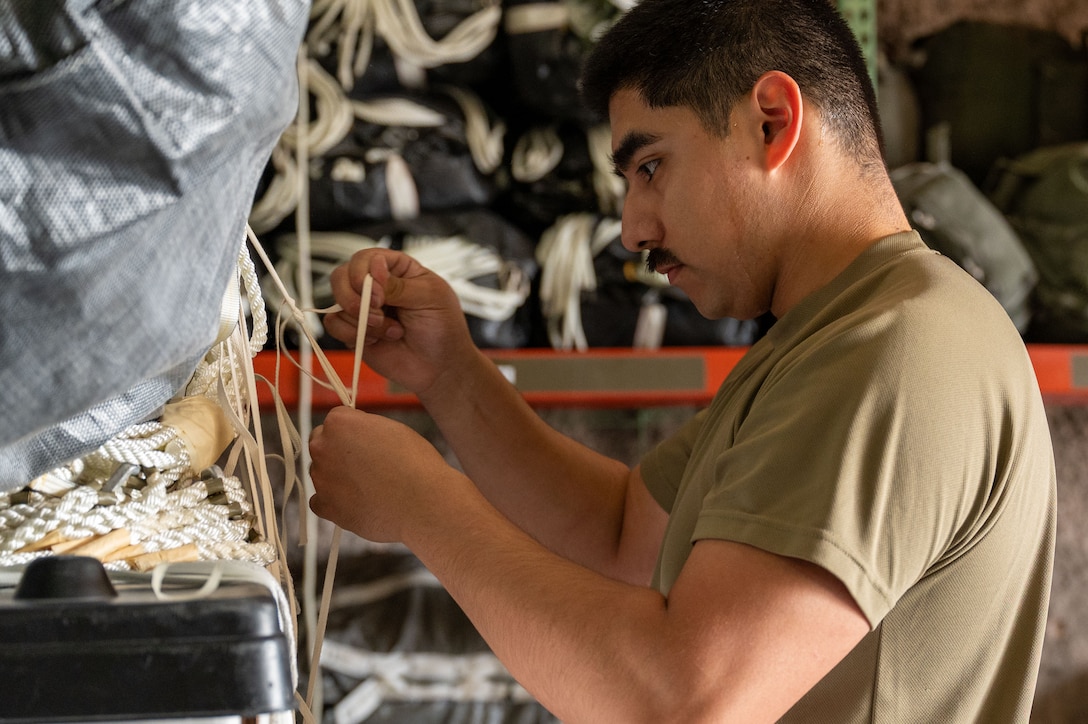 Close up of an Airman tying cord and string