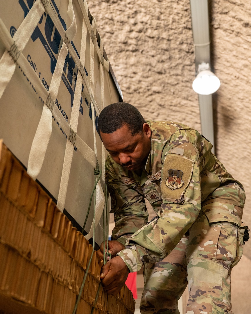 An Airman bends down to tie cord