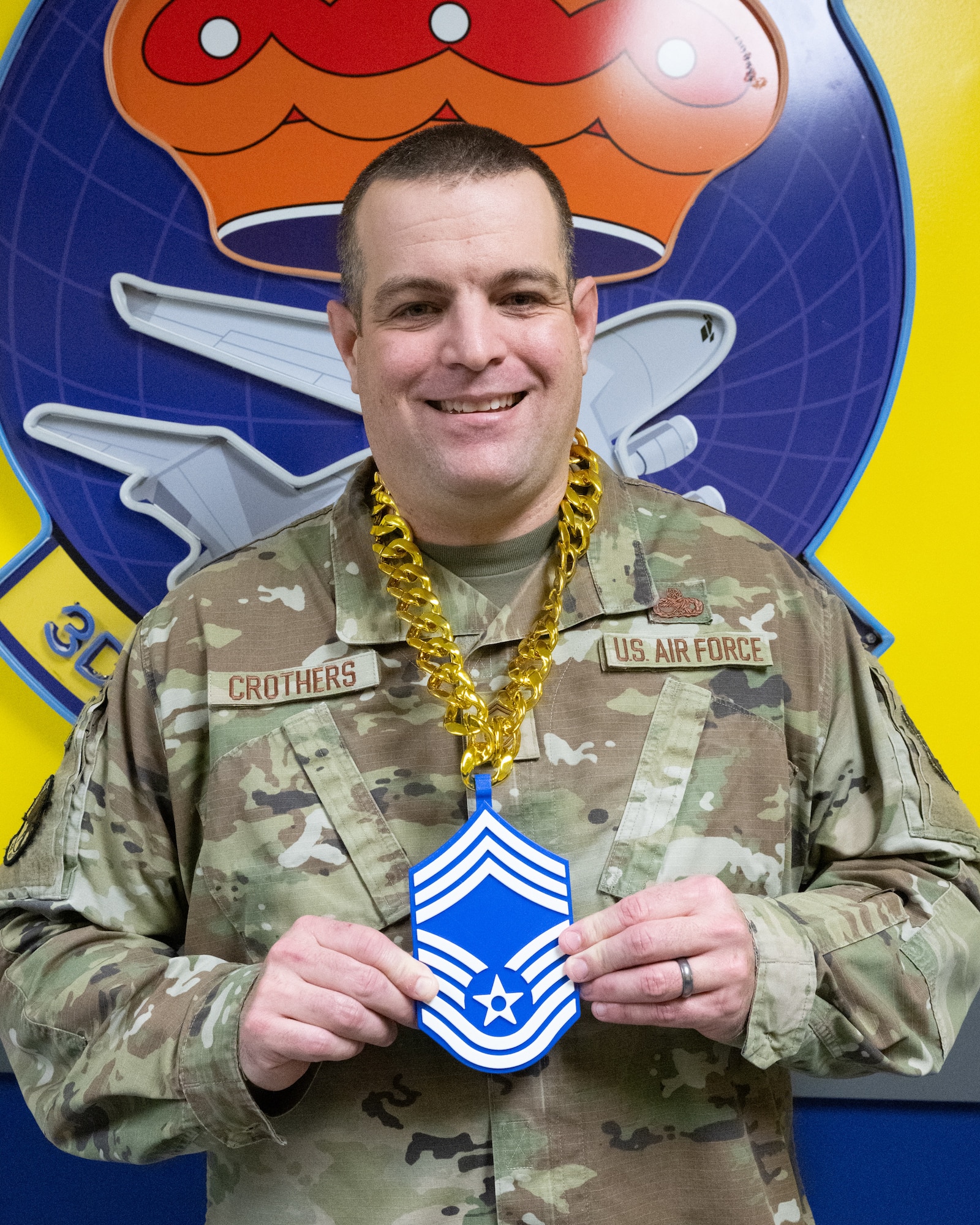 U.S. Air Force Senior Master Sgt. Adam Crothers, 436th Maintenance Squadron maintenance superintendent, shows off his Chief Master Sgt. chain after being notified of his selection for promotion at Dover Air Force Base, Delaware, Jan. 6, 2026. Each selectee was presented with a certificate and personalized gifts from the Dover Chiefs’ Council. (U.S. Air Force photo by Mauricio Campino)