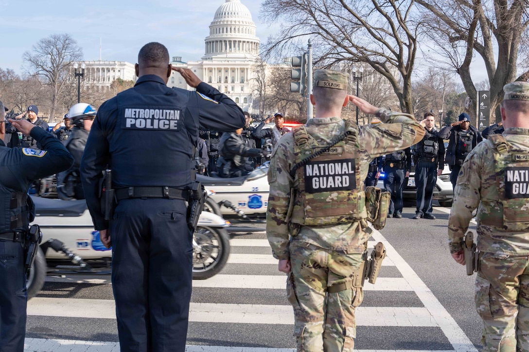 National Guardsmen and police line up to salute a motorcade as it passes in front of the U.S. Capitol.