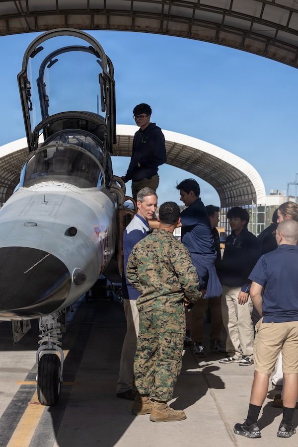 U.S. Marine Corps Master Sgt. Jason Smith, an aircraft maintenance chief, with Marine Fighter Training Squadron 401 (VMFT-401), Marine Aircraft Group 41 (MAG-41), 4th Marine Aircraft Wing (4th MAW), tours teachers and students from Yuma Catholic High School (YCHS) throughout the VMFT-401 hangar during a field trip at Marine Corps Air Station Yuma, Arizona, Dec. 11, 2025. The tour featured educational displays of military aircraft for YCHS aviation students to explore the vital roles they play in combat arms. (U.S. Marine Corps photo by Lance Cpl. Christopher J. Castro)