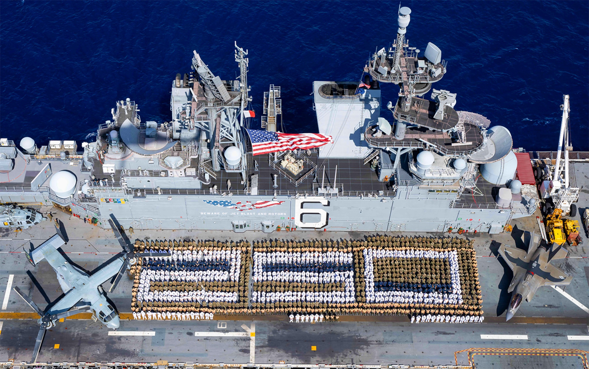 Sailors assigned to the forward-deployed amphibious assault ship USS America (LHA 6) and U.S. Marines with the 31st Marine Expeditionary Unit (MEU) stand in formation for a photo commemorating 250 years of naval service, while conducting operations in the Coral Sea, Aug 2, 2025. (U.S. Navy photo illustration by Mass Communication Specialist Seaman Sam McNeely)