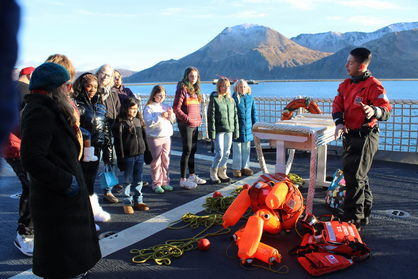 U.S. Coast Guard Seaman Julian Hugg, assigned to USCGC Kimball (WMSL 756), demonstrates deck seamanship equipment to Unalaska community members during the 'Kimball Express' holiday event in Dutch Harbor, Alaska, Dec. 18, 2025. The event welcomed 239 visitors and was held to foster strong relationships between the Coast Guard and the local community. (U.S. Coast Guard photo by Ensign James Griswold)
