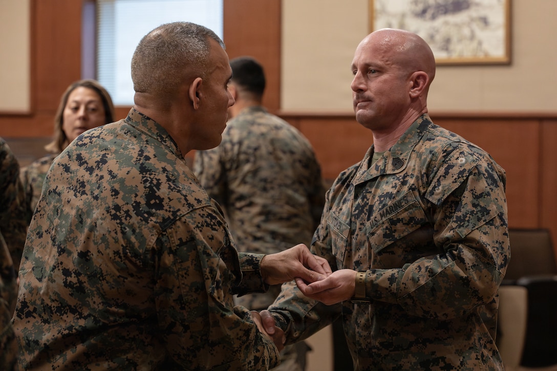 U.S. Marine Corps Sgt. Maj. Edwin A. Mota, command senior enlisted leader of Marine Forces Reserve and Marine Forces South, left, congratulates 1st Sgt. Joseph B. Stoker, an individual material readiness list coordinator with 4th Marine Aircraft Wing, during a redesignation ceremony, Marine Corps Support Facility, New Orleans, Jan. 7, 2025. Stoker became one of the first Marines to laterally transfer to first sergeant through the E-8 redesignation board pilot, a new program within the Marine Corps that allows qualified master sergeants to apply for redesignation as first sergeants. (U.S. Marine Corps photo by Lance Cpl. Van Hoang)