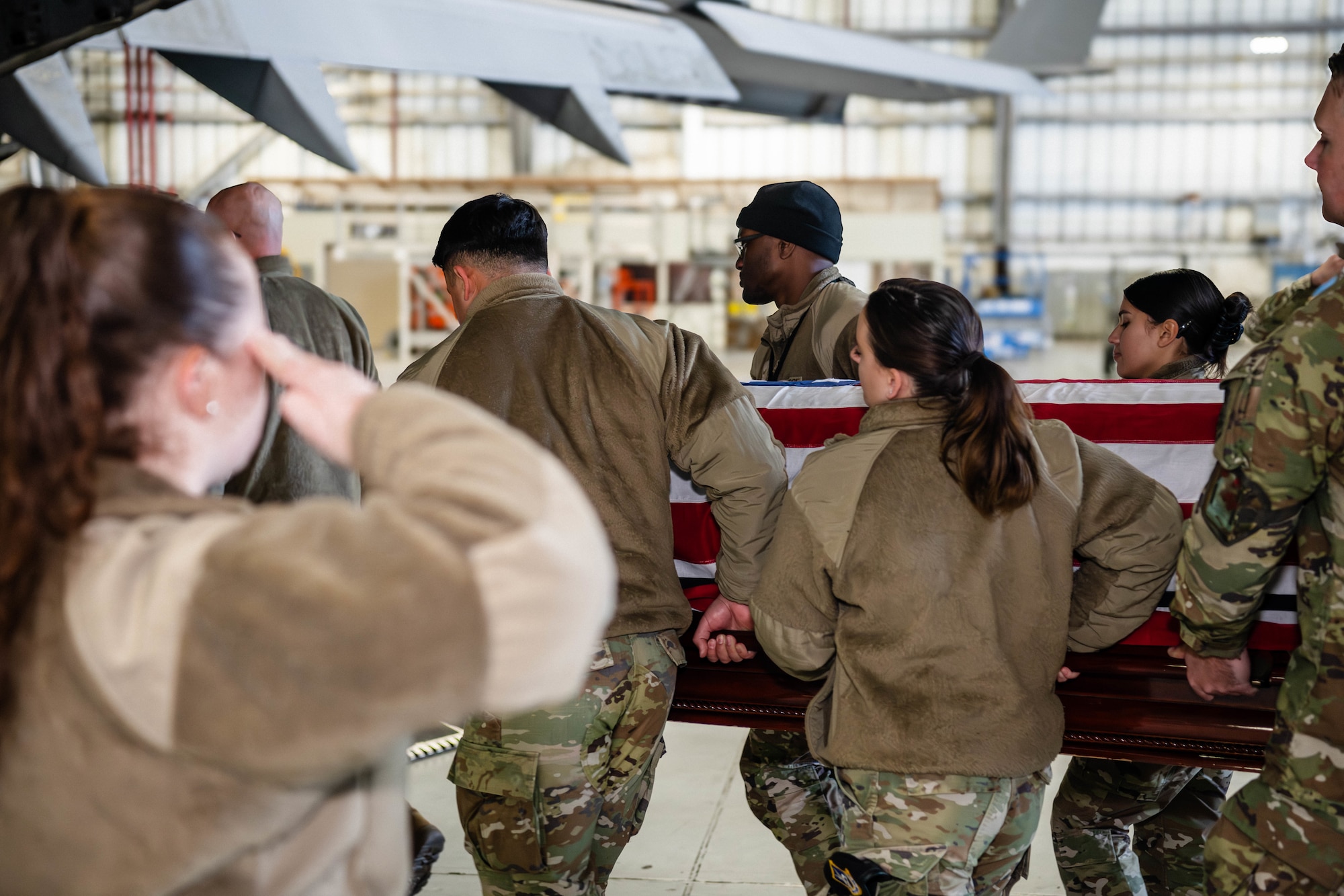 A photo of a group of Airmen carrying a casket while being saluted.