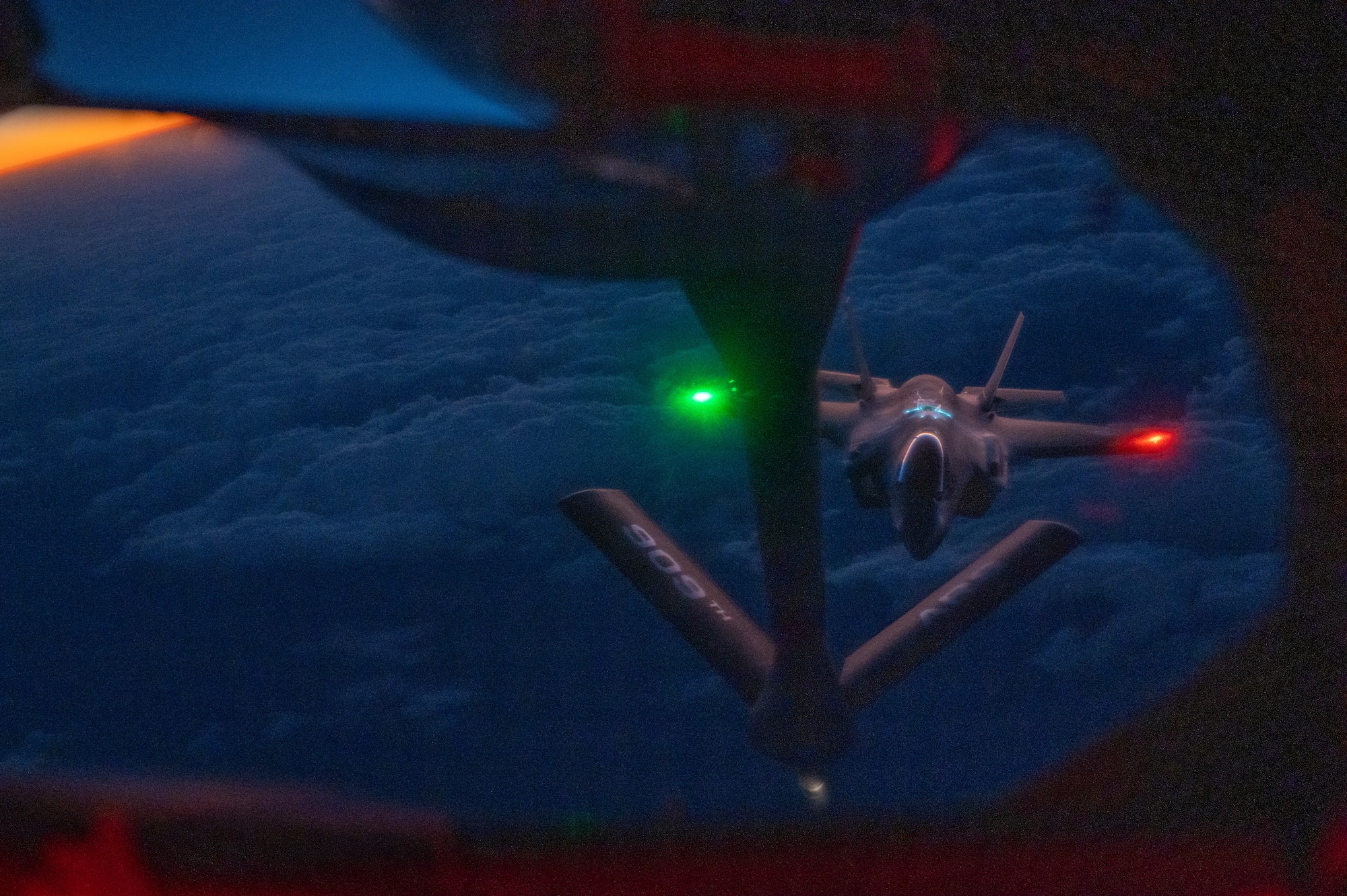 F-35A lightning ll fighter jet flies at night towards a boom pod window