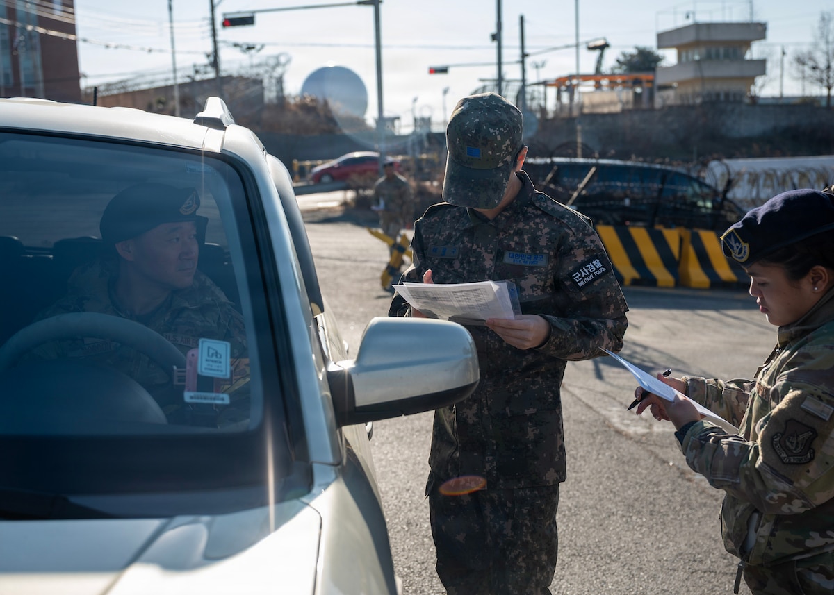 Republic of Korea air force Staff Sgt. Lee Joe Goo, ROKAF military police, is evaluated on entry procedures at Osan Air Base, Republic of Korea, Jan. 5, 2026. All members are trained on installation entry ID requirements, Defense Biometric Identification System operation, escort and pass violation procedures, gate runner procedures, DUI enforcement, and random vehicle searches to ensure that both forces operate with the same expectations, standards, and responsibilities. (U.S. Air Force photo by Staff Sgt. Sarah Williams)

대한민국 공군 군사경찰 이조구 병장이 2026년 1월 5일 오산기지에서 출입 절차에 대한 평가를 받고 있다. 모든 구성원은 기지 출입 신분증 확인, 국방 생체인식 시스템(DBIS) 운용, 방문객지원 및 출입증 위반 절차, 무단침입사고 절차, 음주운전 단속, 무작위 차량 수색 등에 대한 훈련을 받으며, 이는 한미가 동일한 기대치, 기준 및 책임을 가지고 작전을 수행하도록 보장한다. (사진: 사라 윌리엄스 병장)