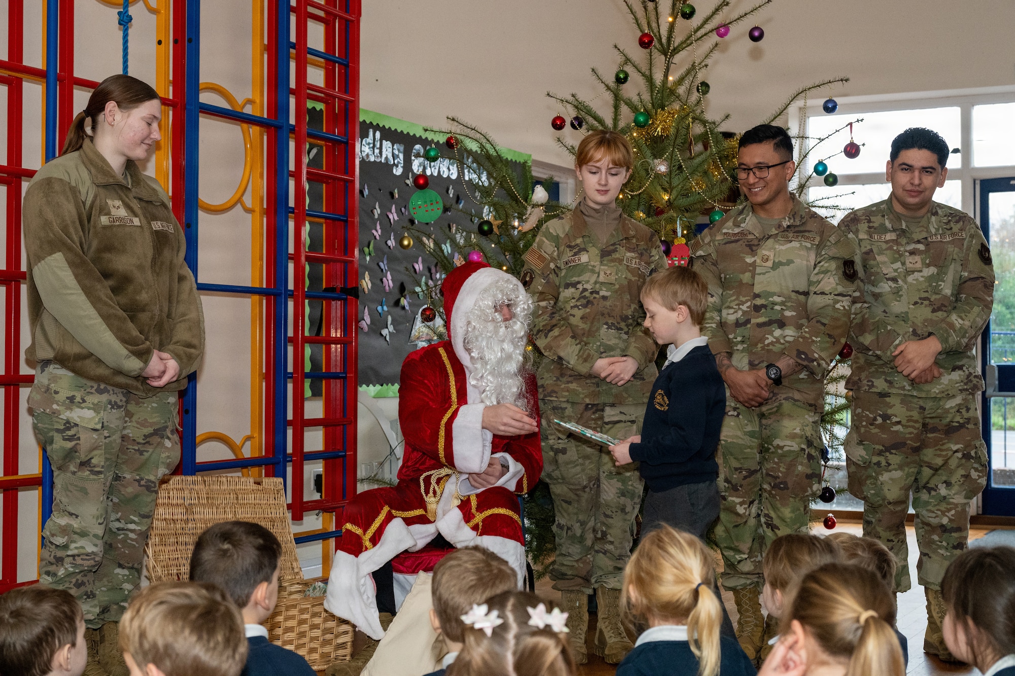 Santa Claus and his helpers assigned to the 420th Munitions Squadron (MUNS) hands a gift to a child