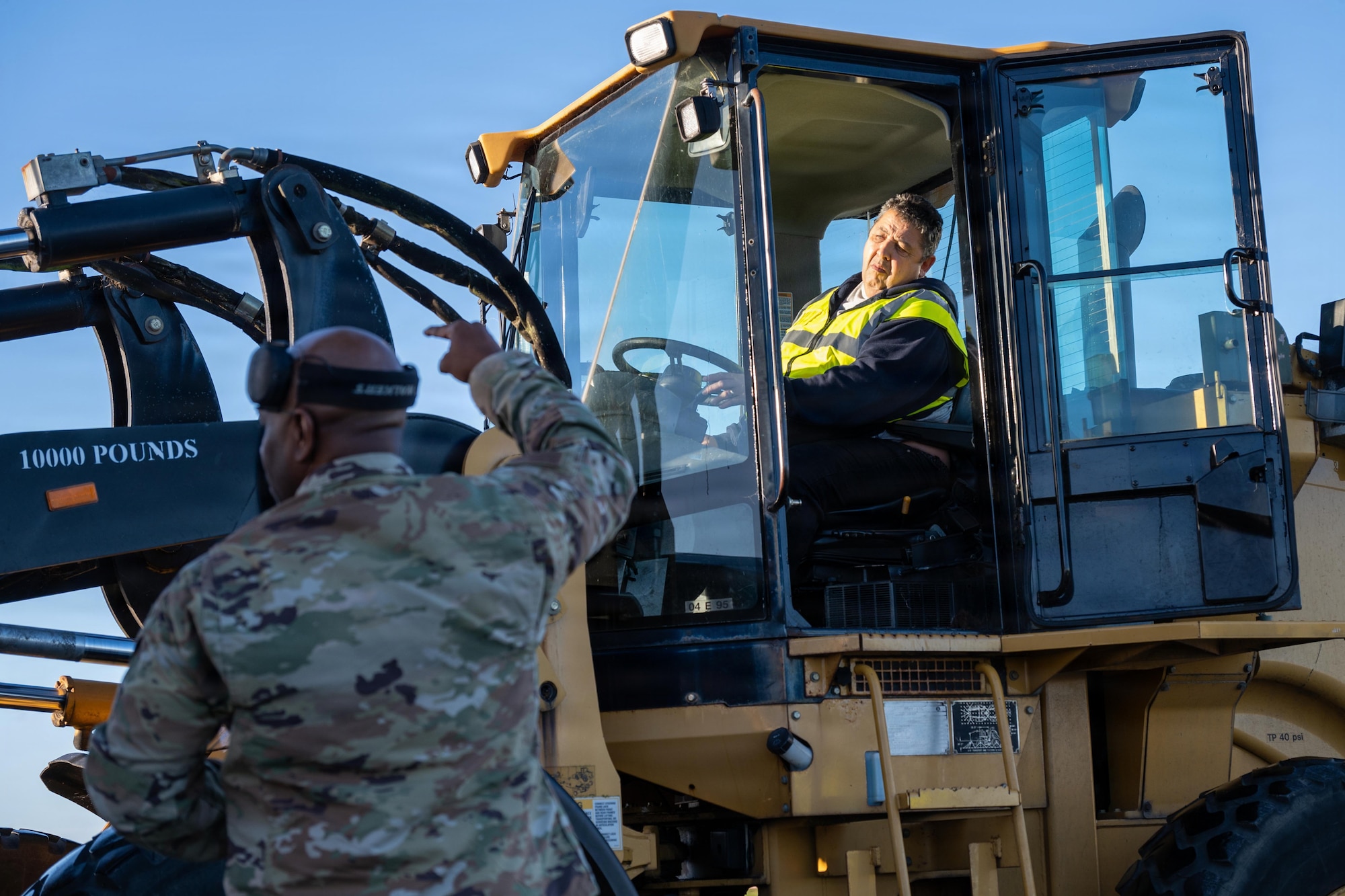U.S. Air Force Master Sgt. Justin George, 420th Air Base Squadron air operations manager, signals a ground transportation operator during cargo movement operations
