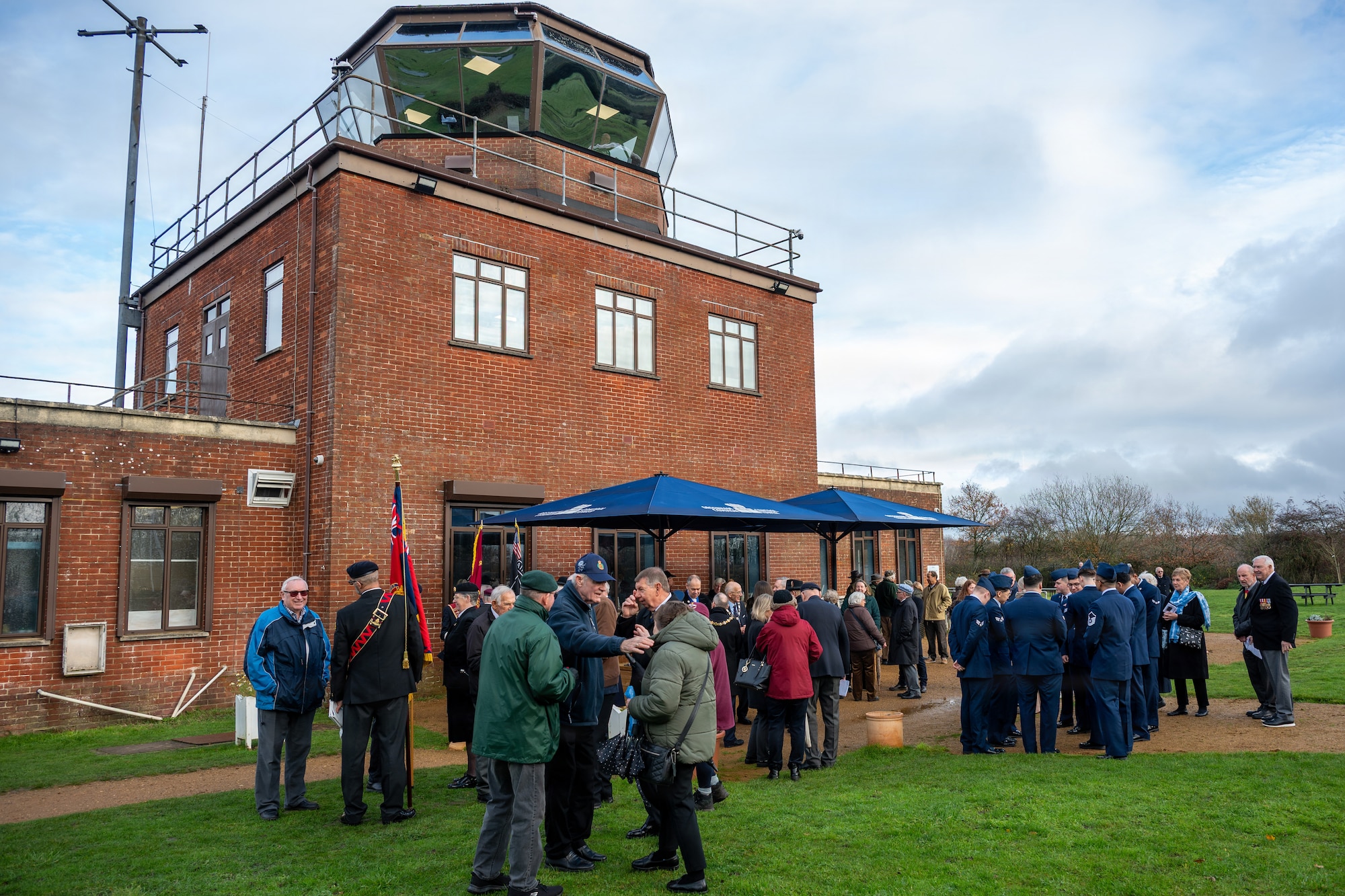 Members of the Royal British Legion, U.S. Air Force Airmen, and local community members gather following a memorial service