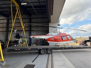 A flatbed tows a military aircraft from an airport hangar.