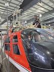 A uniformed service member stands with a military aircraft inside a hangar.