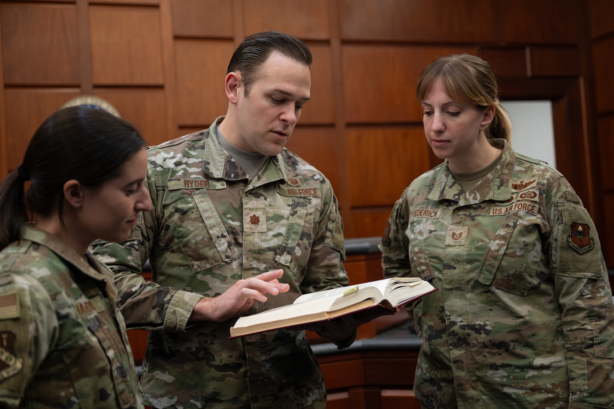 Capt. Abbigale Harris, left, 42d Air Base Wing Judge Advocate chief of military justice, Maj. Stephan Ryder, deputy staff, and Tech. Sgt. Leslie Frederick, noncommission officer in charge of the justice section, all assigned to the 42d Air Base Judge Advocate office, references legal requirements at Maxwell Air Force Base, Alabama, Dec. 06, 2026.