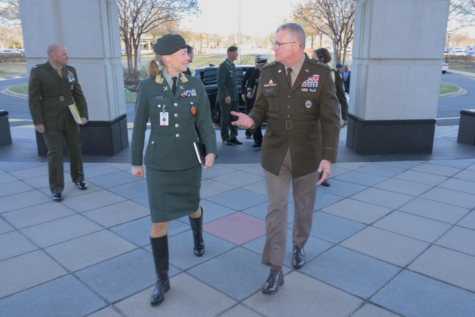 A woman and man in military uniforms walk outside