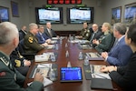 Military leaders from the Defense Logistics Agency and Norway sit at a table in a conference room for a meeting.