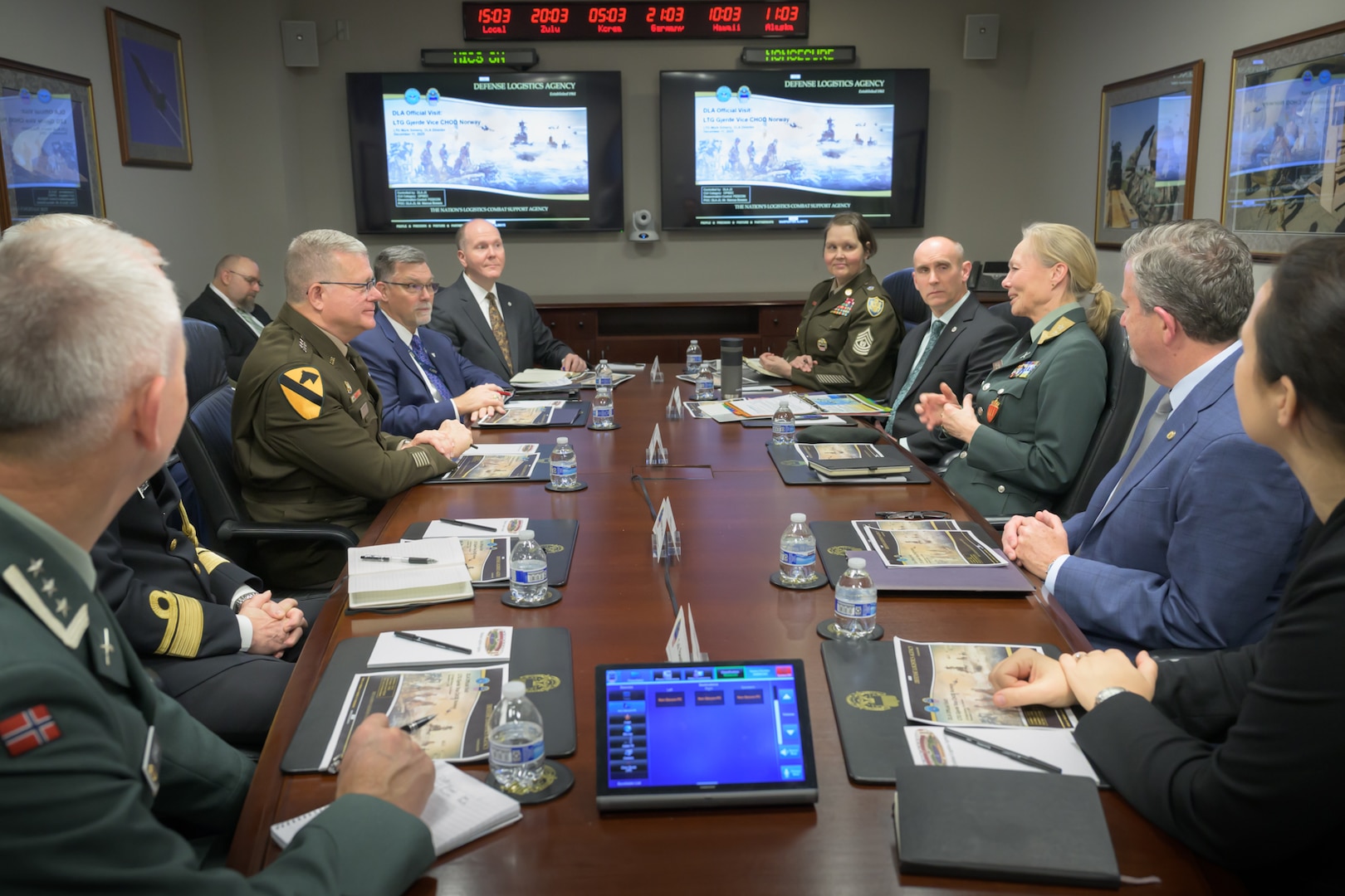 Military leaders from the Defense Logistics Agency and Norway sit at a table in a conference room for a meeting.